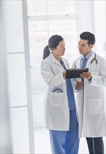 Doctors using digital tablet in hospital corridor