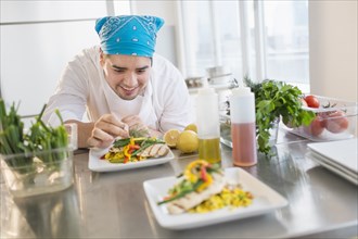 Mixed race chef plating food in restaurant