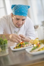 Mixed race chef plating food in restaurant