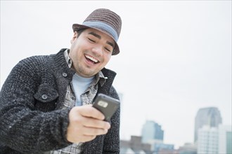Mixed race man using cell phone in city