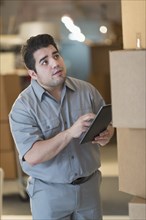 Mixed race worker counting boxes in warehouse