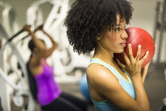 African American woman holding medicine ball in gym