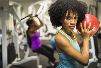 African American woman holding medicine ball in gym