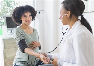 African American doctor taking pregnant woman's blood pressure
