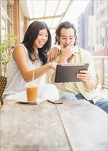 Couple using digital tablet at sidewalk cafe