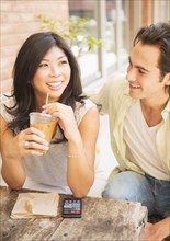 Couple enjoying iced coffee at sidewalk cafe