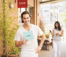Man holding Open sign by cafe