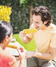 Couple eating corn on the cob outdoors