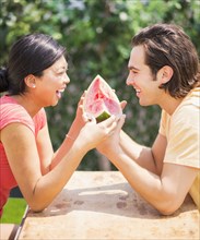 Couple sharing watermelon slice outdoors
