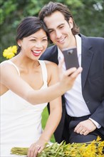 Newlywed couple taking self-portrait at wedding reception