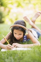 Mixed race girl listening to headphones and drawing outdoors