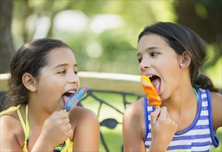 Mixed race girls eating flavored ice outdoors