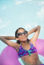 Mixed race girl floating in swimming pool