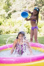Mixed race girls splashing in wading pool
