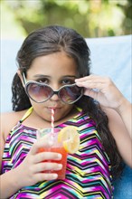 Mixed race girl sipping juice at poolside