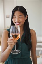 Chinese woman drinking glass of rose wine