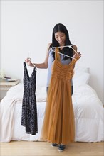Chinese woman picking out dresses in bedroom