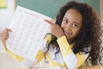 Mixed race student showing off A plus grade in classroom