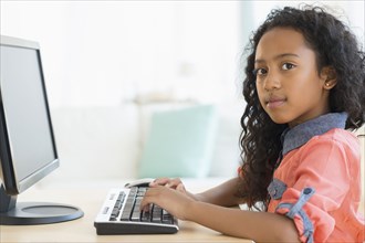 Mixed race girl using computer at desk