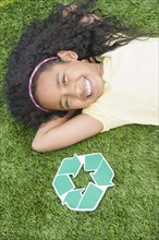 Mixed race girl with recycle symbol in grass