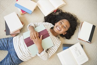 Mixed race girl laying on floor with books