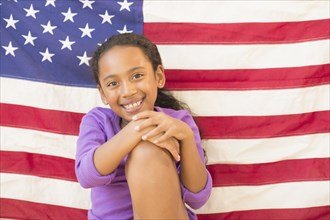 Mixed race girl smiling by American flag
