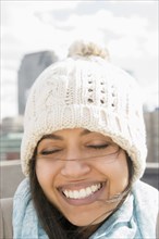 Close up of Asian woman smiling in knit hat with eyes closed