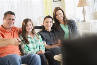 Caucasian family watching TV in living room