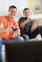 Caucasian father and son playing video games in living room