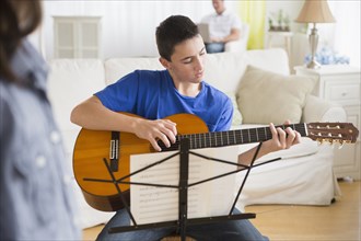 Caucasian boy practicing guitar in living room
