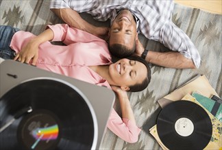 Happy couple on rug listening to record player