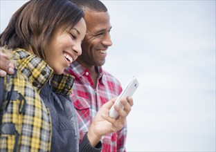 Happy couple using cell phone outdoors