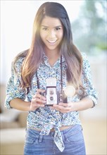 Portrait of smiling Hispanic woman with antique camera