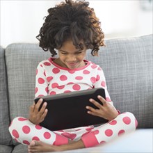 Close up of African American girl in pajamas using digital tablet
