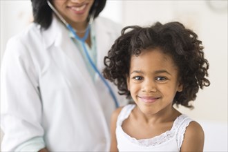 Portrait of smiling African American girl with doctor