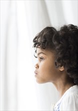 Close up of pensive African American girl looking out window