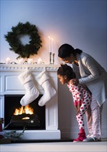 Black mother and daughter looking at Christmas stockings