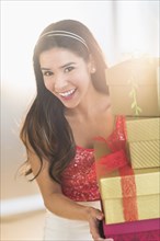 Portrait of smiling Hispanic woman carrying Christmas gifts