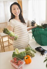 Portrait of pregnant Japanese woman unloading groceries