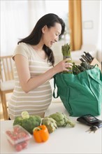 Pregnant Japanese woman unloading groceries