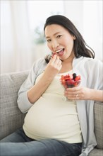 Portrait of pregnant Japanese woman eating berries