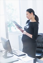 Pregnant Japanese businesswoman using digital tablet