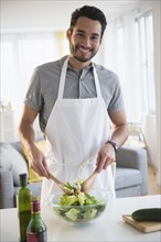 Mixed race man tossing salad at table