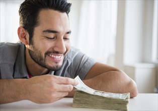 Mixed race man counting stack of money