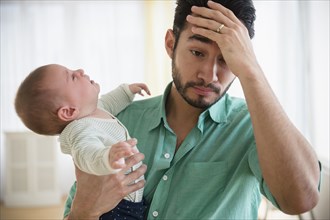 Frustrated father holding crying baby
