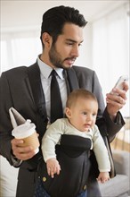 Businessman carrying baby and cell phone