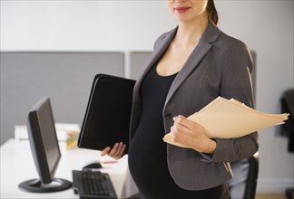 Pregnant Caucasian businesswoman working in office