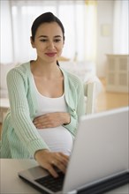 Pregnant Caucasian woman using laptop