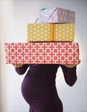 Pregnant Caucasian woman holding wrapped gifts
