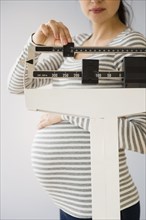 Pregnant Caucasian woman weighing herself